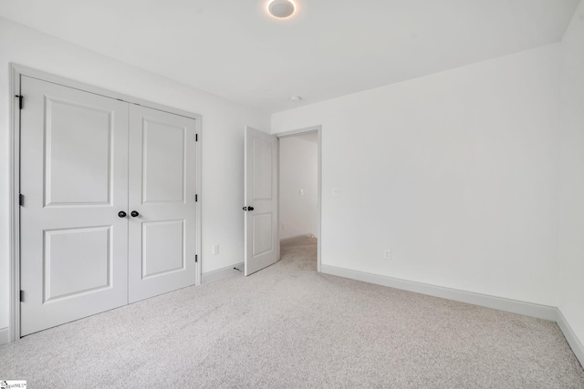 unfurnished bedroom with light colored carpet and a closet