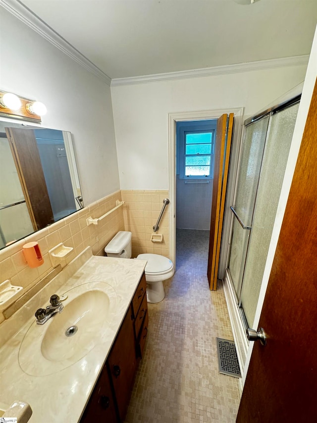 bathroom with a shower with door, toilet, tile walls, vanity, and ornamental molding