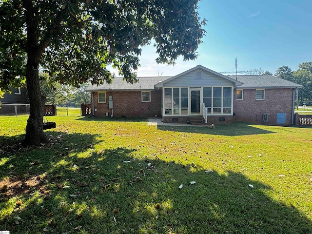 rear view of house with a sunroom and a lawn