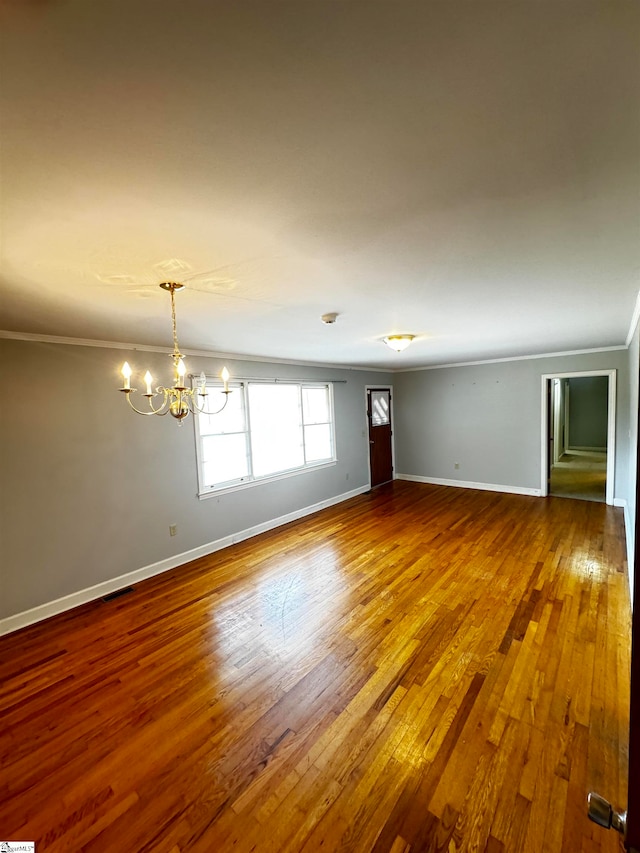 empty room with ornamental molding, hardwood / wood-style floors, and a notable chandelier