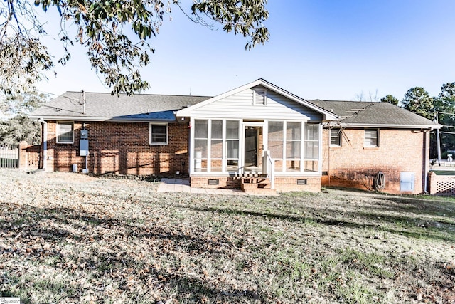 rear view of house with a yard, a patio area, and a sunroom