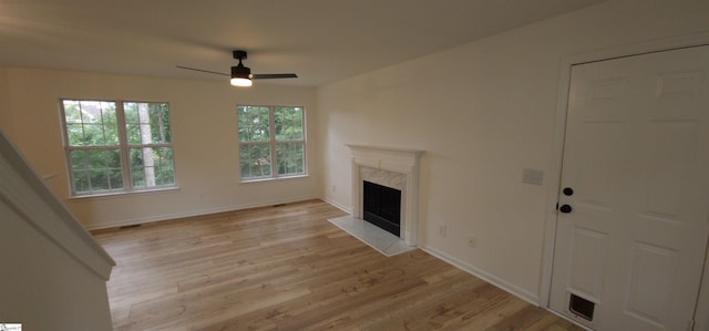 unfurnished living room featuring ceiling fan, light hardwood / wood-style floors, and a high end fireplace