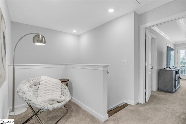 sitting room with ornamental molding and light carpet