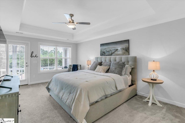 carpeted bedroom with ceiling fan, a raised ceiling, crown molding, and access to exterior