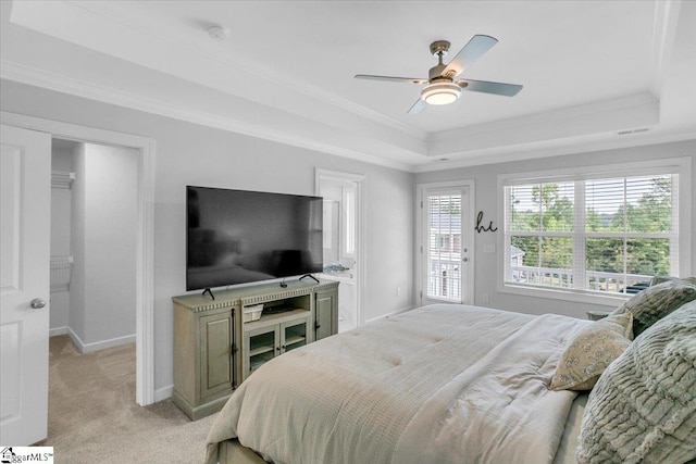 carpeted bedroom with crown molding, a tray ceiling, and ceiling fan