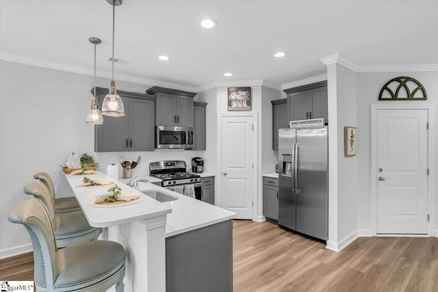 kitchen with sink, kitchen peninsula, hanging light fixtures, light hardwood / wood-style flooring, and appliances with stainless steel finishes