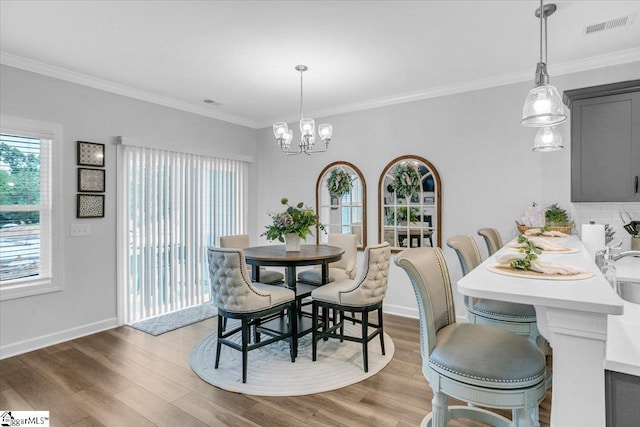 dining room with ornamental molding, light hardwood / wood-style floors, and a notable chandelier