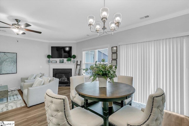 dining room featuring ornamental molding, ceiling fan with notable chandelier, and light hardwood / wood-style floors