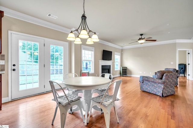 dining room featuring light wood-type flooring, ceiling fan with notable chandelier, and crown molding