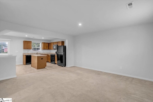 kitchen featuring light carpet, black appliances, a kitchen island, and sink