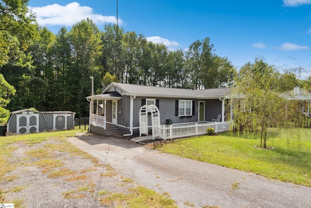 view of front of property featuring a storage shed, covered porch, and a front yard