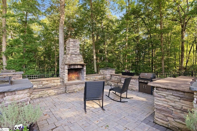 view of patio / terrace featuring grilling area, an outdoor kitchen, and an outdoor stone fireplace