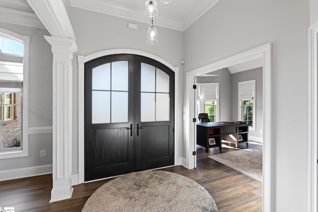 entrance foyer with ornate columns, ornamental molding, dark wood-type flooring, and plenty of natural light