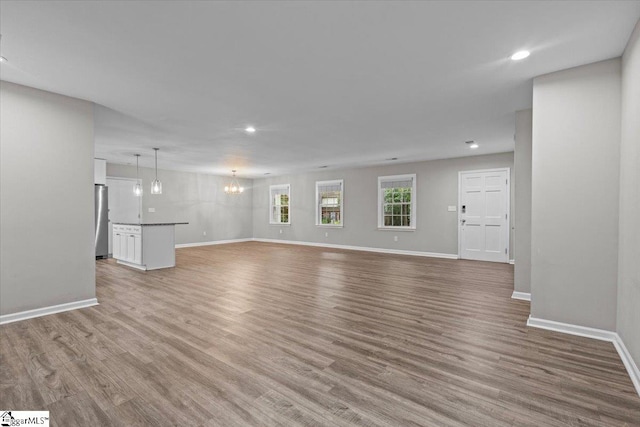 unfurnished living room with light hardwood / wood-style flooring and a notable chandelier