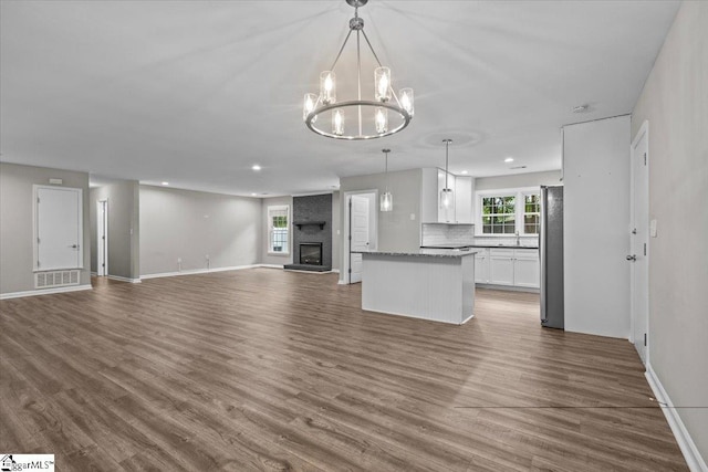 kitchen featuring pendant lighting, white cabinetry, a fireplace, dark hardwood / wood-style flooring, and stainless steel fridge