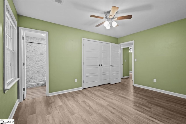 unfurnished bedroom with a closet, ensuite bath, ceiling fan, and light hardwood / wood-style floors