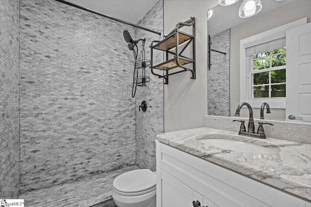 bathroom featuring tiled shower, vanity, and toilet