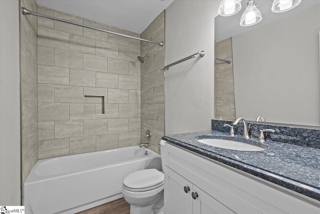 full bathroom with hardwood / wood-style floors, vanity, tiled shower / bath combo, and toilet