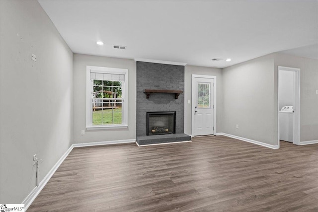 unfurnished living room featuring a brick fireplace and dark wood-type flooring