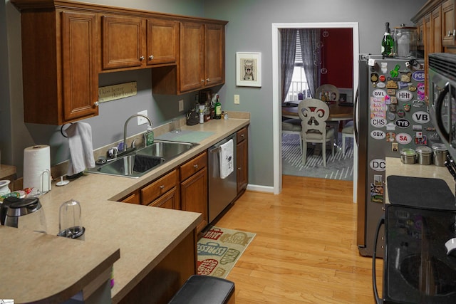 kitchen featuring stainless steel appliances, sink, and light hardwood / wood-style flooring