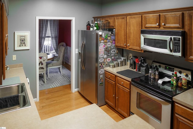 kitchen with sink, stainless steel appliances, and light hardwood / wood-style floors