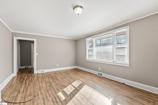 empty room featuring visible vents, crown molding, baseboards, and wood finished floors