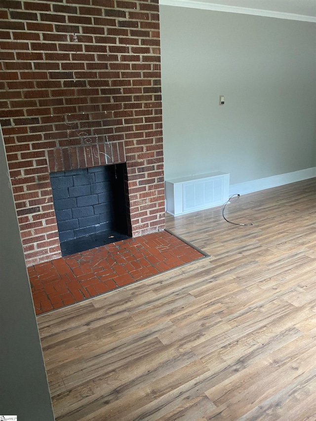 interior details featuring ornamental molding, hardwood / wood-style floors, and a brick fireplace