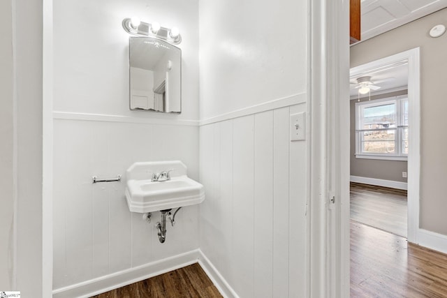 bathroom with a wainscoted wall and wood finished floors