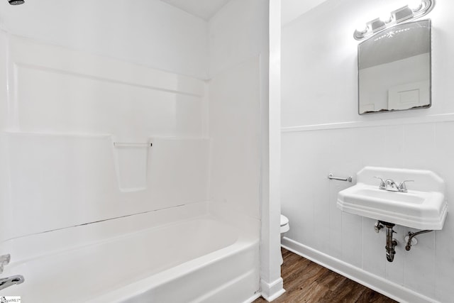 full bathroom featuring toilet, a sink, shower / washtub combination, and wood finished floors