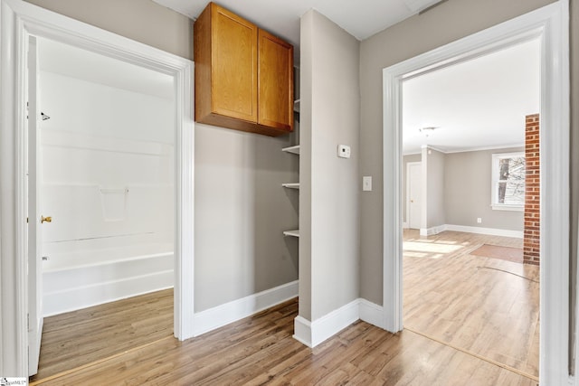 corridor featuring baseboards and light wood finished floors