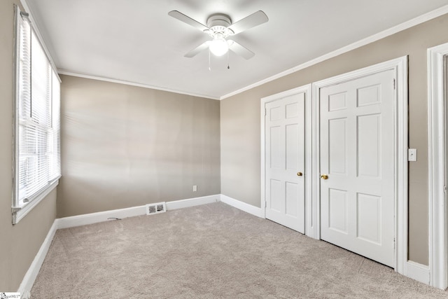 unfurnished bedroom featuring baseboards, carpet, visible vents, and crown molding