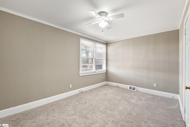 carpeted spare room featuring baseboards, a ceiling fan, visible vents, and crown molding