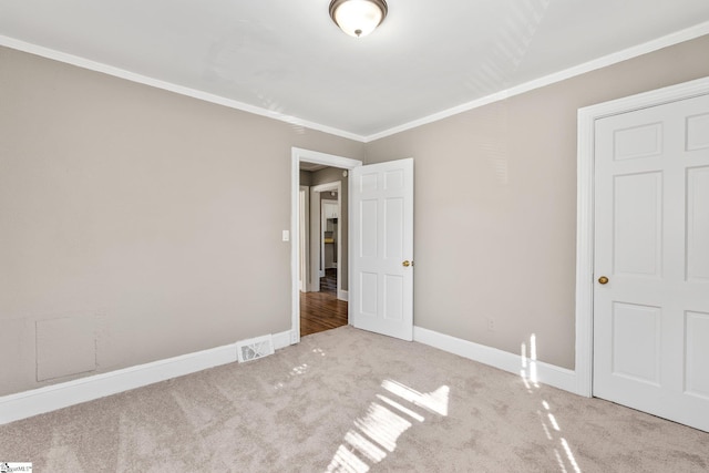 unfurnished bedroom featuring visible vents, baseboards, carpet flooring, and ornamental molding