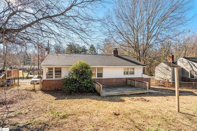 rear view of house with brick siding, a shingled roof, fence, a lawn, and a chimney