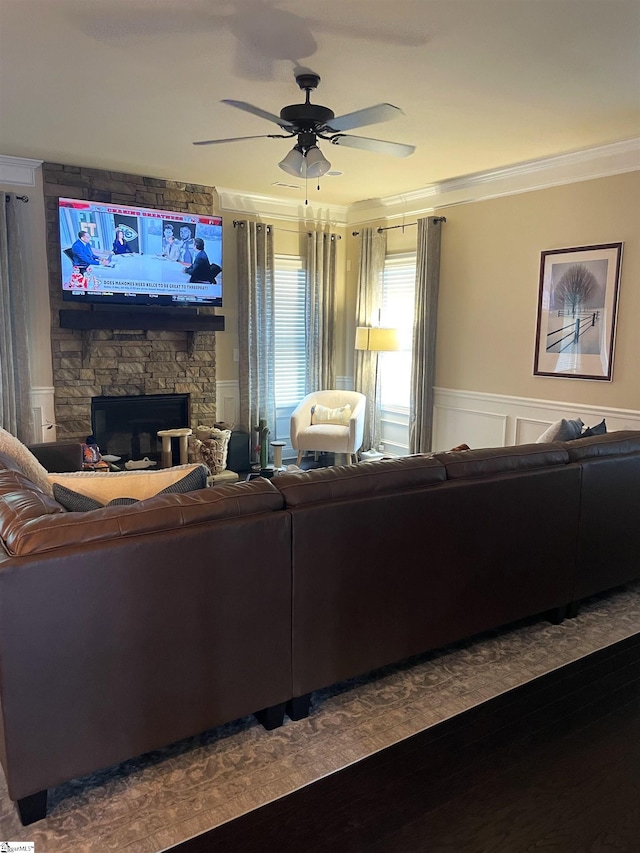 living room featuring crown molding, a stone fireplace, ceiling fan, and hardwood / wood-style flooring