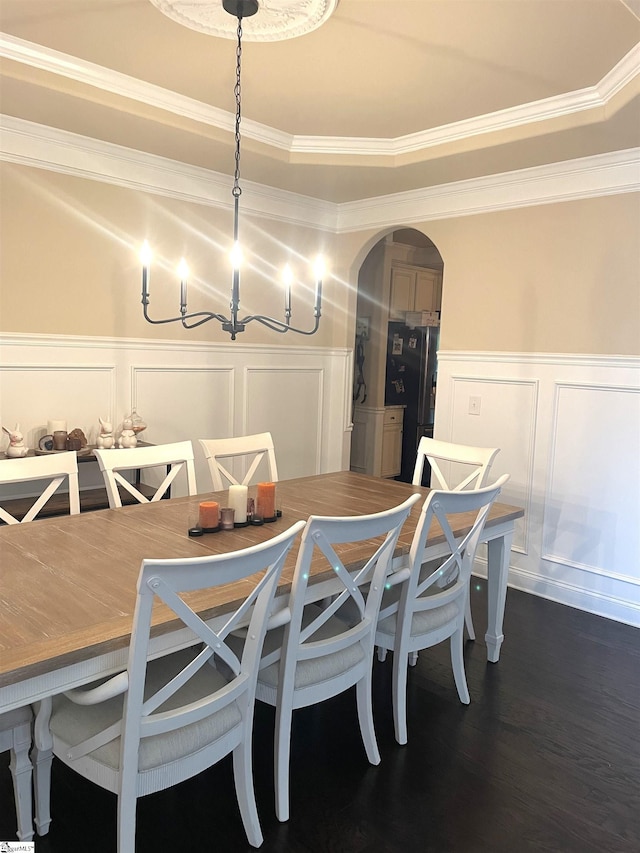 dining space with crown molding, a tray ceiling, and dark wood-type flooring