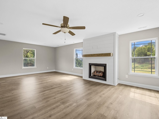 unfurnished living room with a wealth of natural light, light hardwood / wood-style floors, ceiling fan, and a fireplace