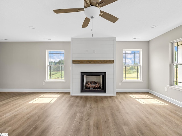 unfurnished living room featuring ceiling fan, a fireplace, and light hardwood / wood-style flooring