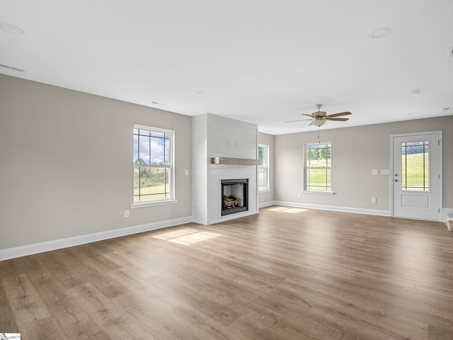 unfurnished living room featuring a large fireplace, ceiling fan, and light wood-type flooring