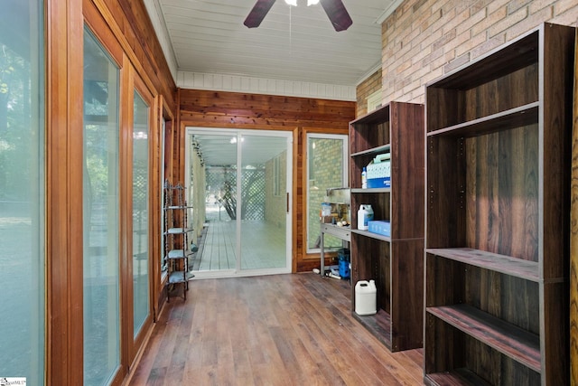 unfurnished office featuring a healthy amount of sunlight, wooden walls, ceiling fan, and hardwood / wood-style flooring