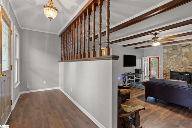 interior space with wood-type flooring, a stone fireplace, ornamental molding, and ceiling fan