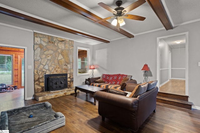 living room featuring ceiling fan, beam ceiling, a stone fireplace, a textured ceiling, and dark hardwood / wood-style floors