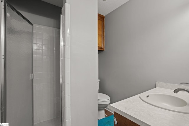 bathroom with a textured ceiling, a shower with door, vanity, and toilet