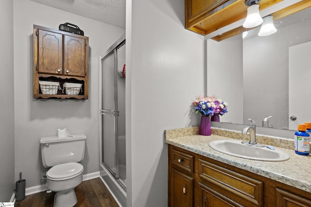 bathroom featuring a textured ceiling, walk in shower, hardwood / wood-style floors, vanity, and toilet