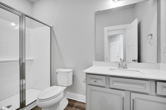 bathroom featuring vanity, wood-type flooring, an enclosed shower, and toilet