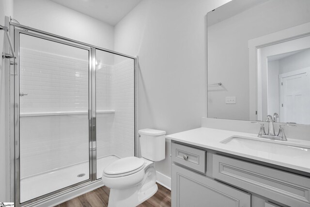 bathroom with vanity, toilet, an enclosed shower, and hardwood / wood-style floors