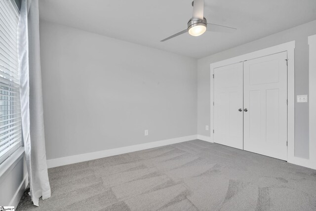 unfurnished bedroom featuring light colored carpet, ceiling fan, and a closet