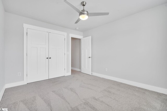 unfurnished bedroom with light carpet, ceiling fan, and a closet