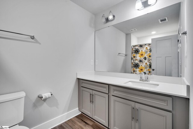 bathroom featuring vanity, hardwood / wood-style floors, walk in shower, and toilet