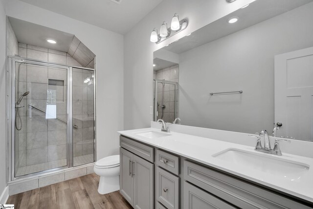 bathroom featuring vanity, toilet, a shower with shower door, and hardwood / wood-style floors